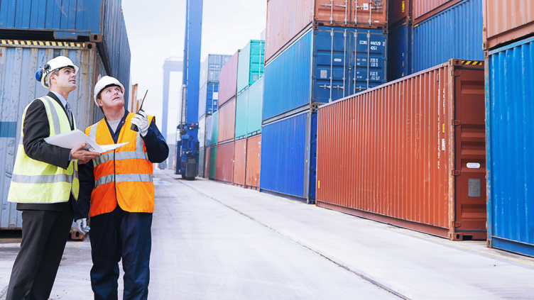 Two coworkers talking next to shipping containers