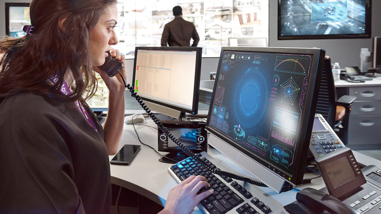 woman on phone looking at computer screen while typing