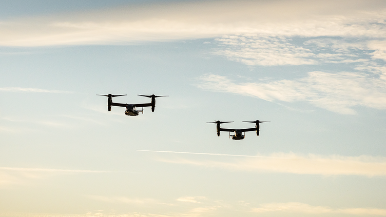 two drones flying in the sky with clouds behind them