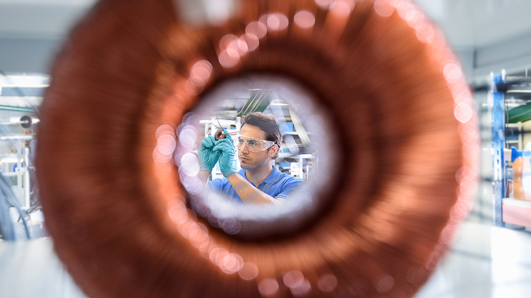 man with protective eye wear and gloves working on coil object