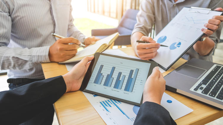 3 people around a table with graphs and charts