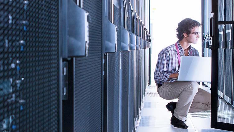 man in server room with laptop