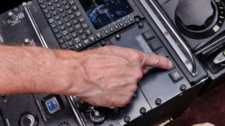 finger pressing a button on airplane instrument panel