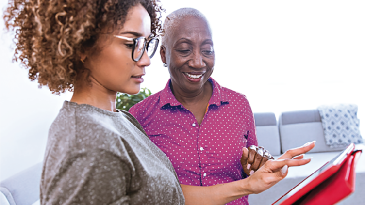 Two ladies smilining while looking at a tablet