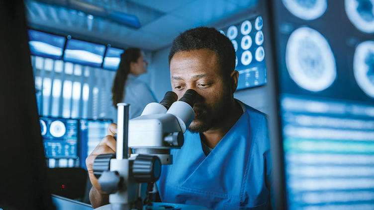 Doctor looking into a microscope surrounded by medical scans and data