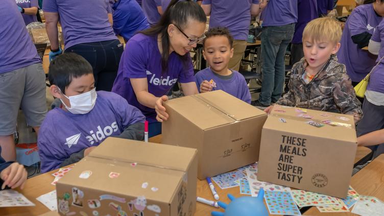 Children packaging meals for generosity feeds community event