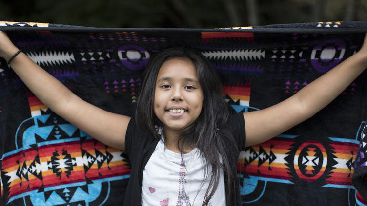 Smiling girl in front of a colorful tribal blanket
