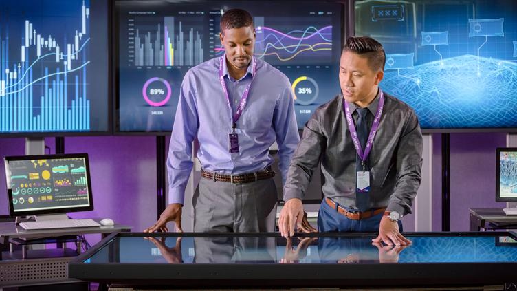 Two men pointing to a touch screen table