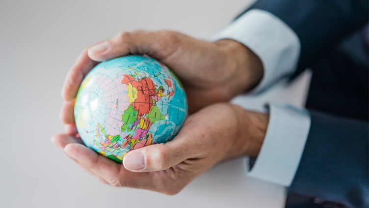 A person cupping their hands holding a small globe