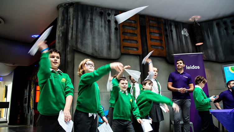 school children throwing paper airplanes