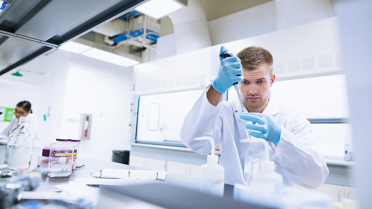 Man in lab putting specimens in test tubesMan in lab putting specimens in test tubes